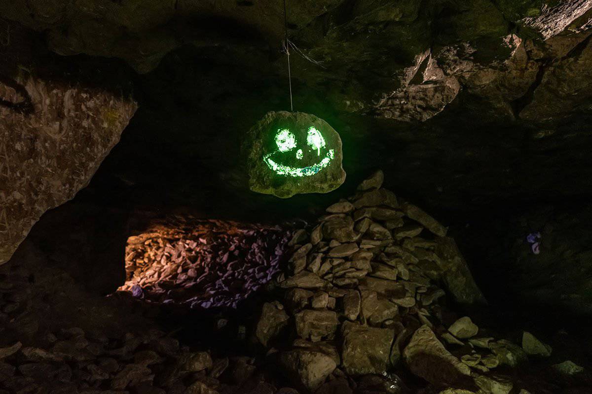 A carved Halloween pumpkin face on a rock inside a dark cave