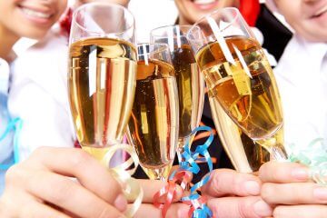 five people raise a glass of wine in celebration.