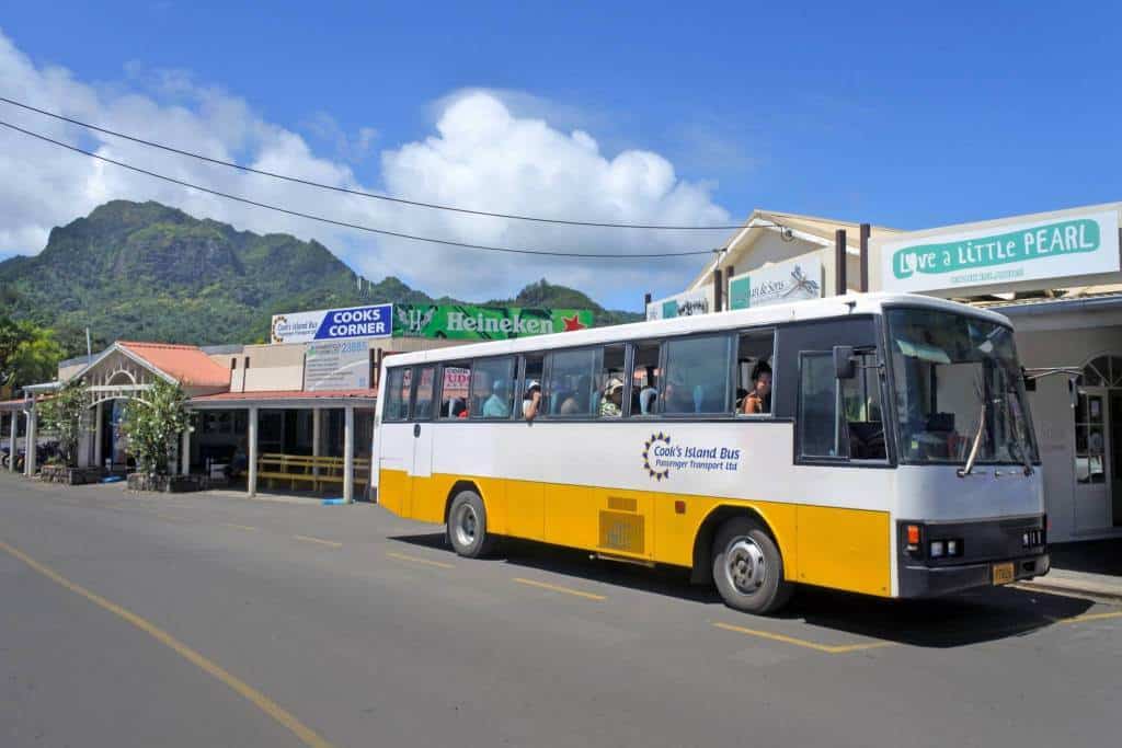 A yellow and white airport transfer bus driving down a street.