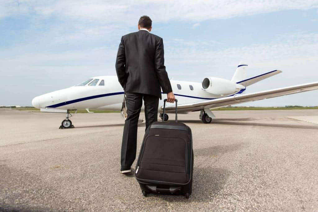 A man in a suit that was just dropped off by Sonic D Limousinewalking towards a small plane for an airport transfer.