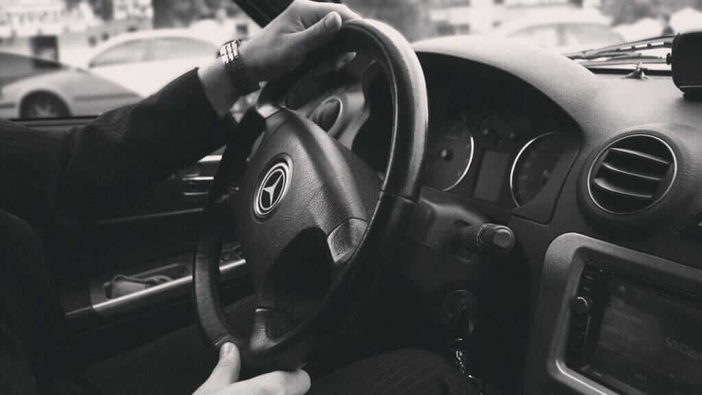 A black and white photo of a man driving a car.