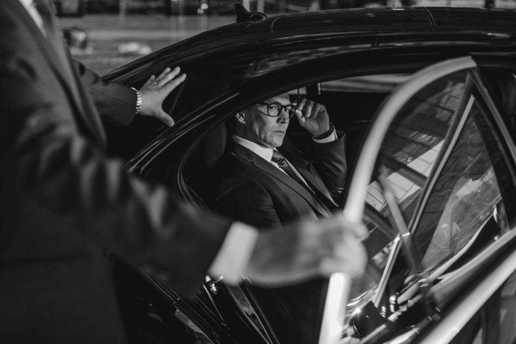A black and white photo of a man getting out of a car.