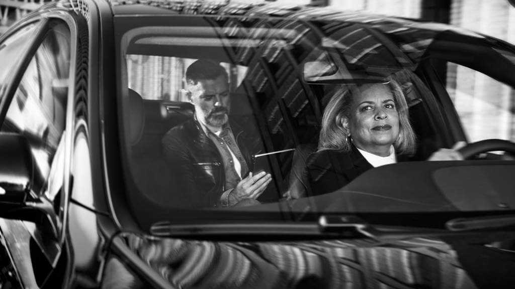 A black and white photo of a couple in a car, showcasing the charm of a chauffeur service.