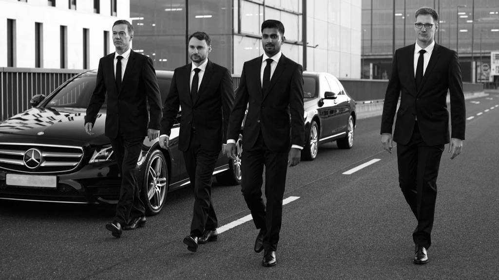 A group of men in suits parade down the street during a lavish Chauffeur Service in New York.