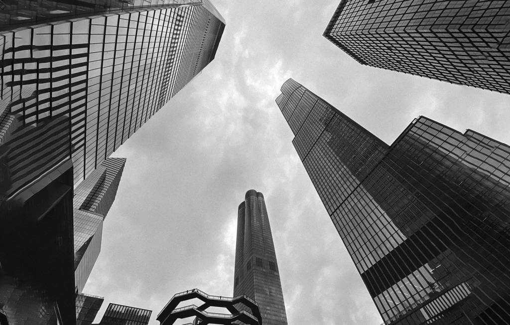 A black and white photo of tall buildings in a city with a chauffeur service in New York.