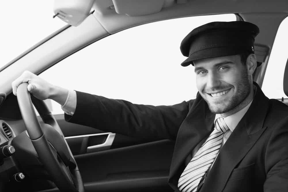 Black and white photo of a Sonic D Limousine Chauffer driving a car.