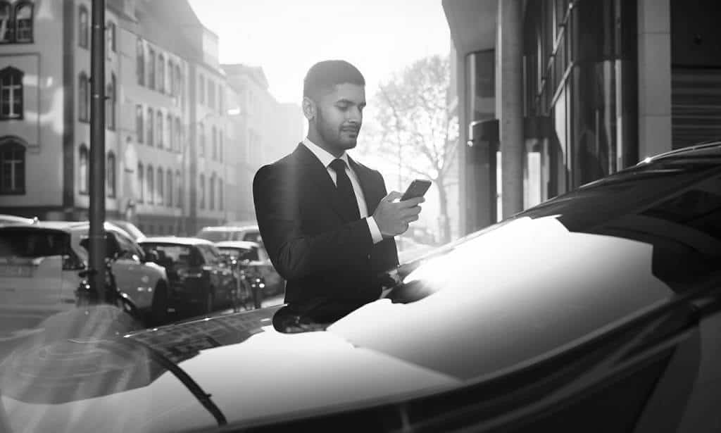 A man in a suit standing next to a Sonic D Limousine Worldwide car.