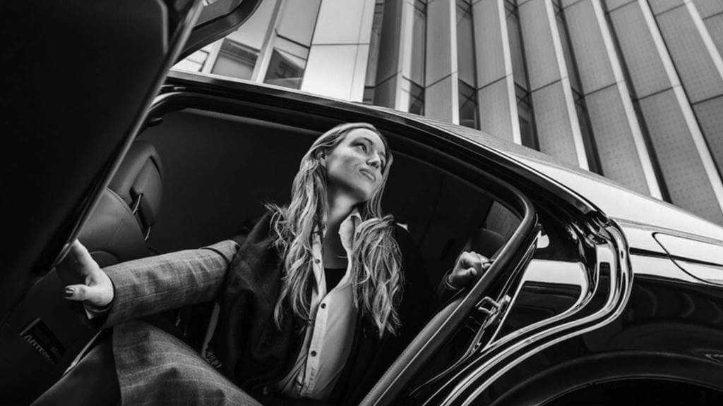 A black and white photo of a woman getting out of a car.