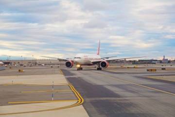 A red and white airplane on a runway at Newark Airport. Sonic D Limousine is waiting for the passenger.