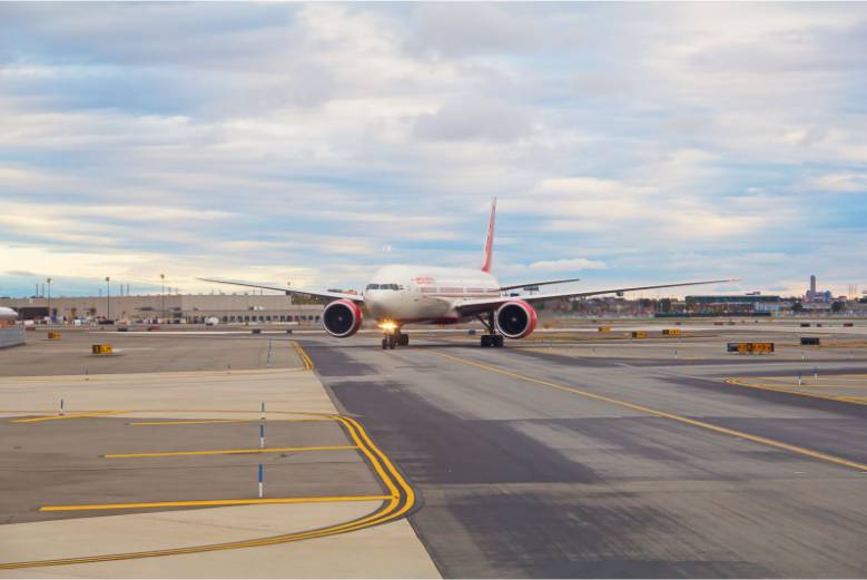 A red and white airplane on a runway at Newark Airport. Sonic D Limousine is waiting for the passenger.