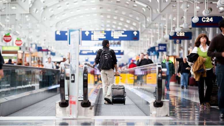 A group of people walking down an escalator at Newark Airport's transportation area.