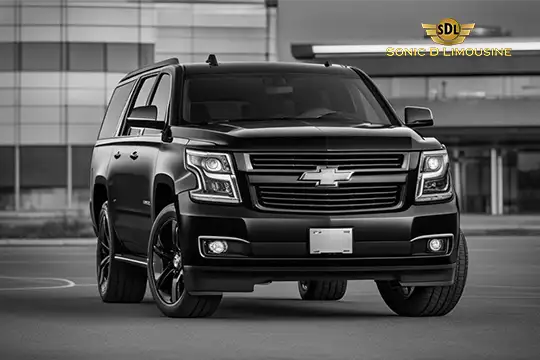 Sonic D Limousine Worldwide Voted Most Reliable Airport Transportation Provider! A black SUV with a Chevrolet logo is parked in front of a modern building, representing Sonic D Limousine, your go-to for luxury airport transportation. The &quot;Sonic D Limousine&quot; logo is prominently displayed in the top right corner. Sonic D Limousine Worldwide your luxury Airport Transportation