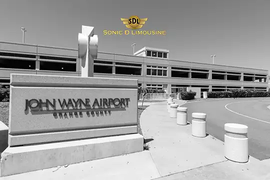 Sonic D Limousine Worldwide Voted Most Reliable Airport Transportation Provider! A black and white photo of the entrance sign for John Wayne Airport in Orange County, with a multi-level parking structure in the background, captures the essence of Sonic D Limousine's luxury airport transportation service. Sonic D Limousine Worldwide your luxury Airport Transportation