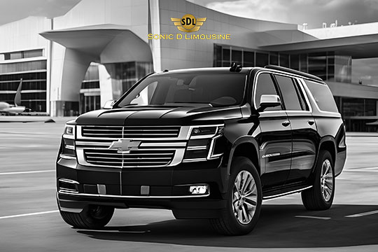 Sonic D Limousine Worldwide Voted Most Reliable Airport Transportation Provider! A Black Chevrolet Suburban, emblazoned with the Sonic D Limousine logo, is parked in front of a modern airport terminal, epitomizing luxury airport transportation. Sonic D Limousine Worldwide your luxury Airport Transportation