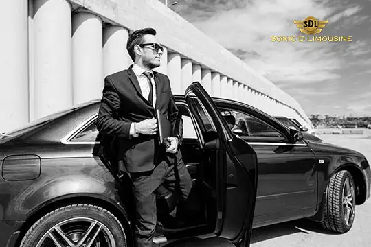 Sonic D Limousine Worldwide Voted Most Reliable Airport Transportation Provider! A man in a suit and sunglasses steps out of an Audi car, with the logo "Sonic D Luxury Airport Transportation" visible in the top right corner. Sonic D Limousine Worldwide your luxury Airport Transportation