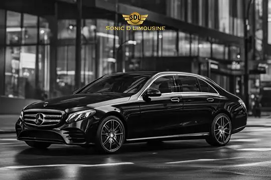 Sonic D Limousine Worldwide Voted Most Reliable Airport Transportation Provider! A black Mercedes-Benz sedan, marked with the "Sonic D Limousine" logo, elegantly parked on a city street at night. Representing luxury airport transportation, the vehicle radiates sophistication against the urban backdrop. Sonic D Limousine Worldwide your luxury Airport Transportation