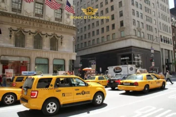 Sonic D Limousine Worldwide Voted Most Reliable Airport Transportation Provider! Several yellow taxis are driving and parked on a busy street in front of the Elizabeth Arden building and various shops in a city. An SDL Sonic D Limousine logo is superimposed on the image, adding a touch of luxury to the bustling urban scene. Sonic D Limousine Worldwide your luxury Airport Transportation